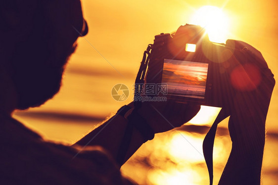 在日落时使用其专业数码SLR摄影机的男子旅行数码摄影概念照片图片