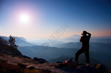 专业摄影师在岩石高峰用镜像相机拍摄照片图片