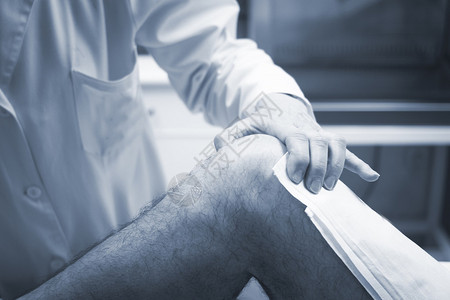 外科医生骨科医生检查中年男患者以确定受伤疼痛活动能力并诊断腿部膝关节半月板软骨脚踝和足背景图片