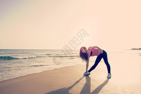 一名在沙滩上做健身锻炼的年轻女子使图片