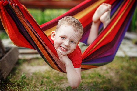 美丽的快乐的小男孩在吊床里休息玩得开心图片