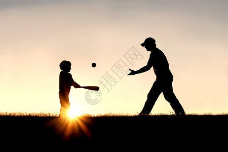 一个父亲和他年幼的孩子在外面打棒球的剪影图片