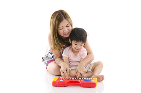 可爱的母亲教她儿子在白背景上弹电玩具钢图片