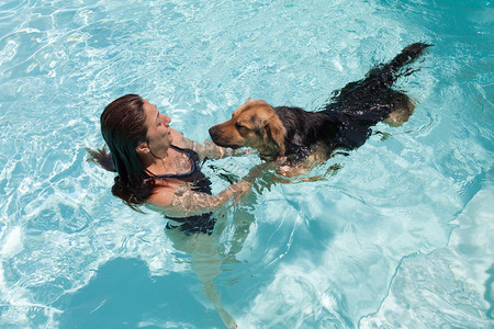 女人和她的狗在游泳池里游泳图片