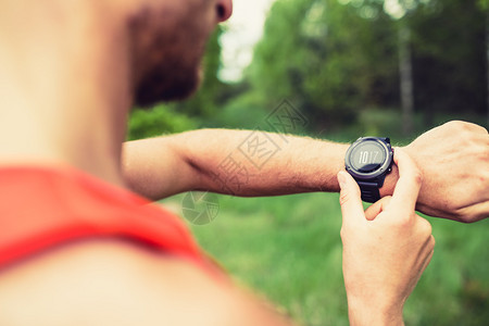 跑步者在山林小径上查看运动手表智能手表越野跑步者检查能GPS位置或心率脉冲夏季小径上户外使用的运动智能手图片