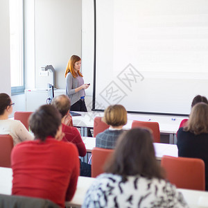演讲者在大学报告厅发表演讲学员听课并做笔记在白屏上背景图片