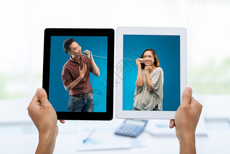 年轻亚洲男子使用锡手机在数字平板电脑上为女友照片歌唱一首歌背景图片