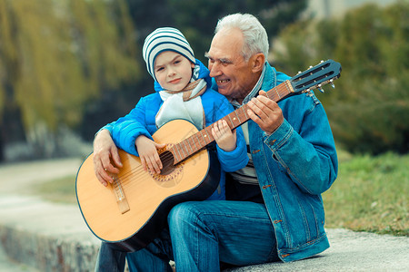 祖父和孙子在公园户外弹吉他图片