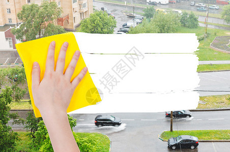 手从图象上用黄色抹布删除街上的雨图片