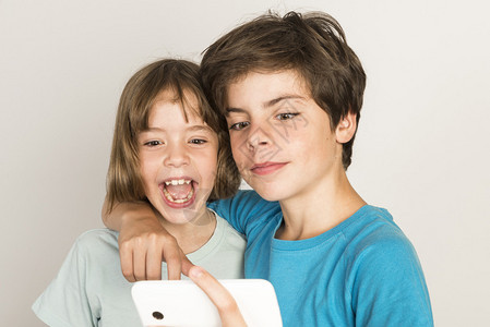 快乐的孩子拿一个自拍在家中使用智能手机孤图片
