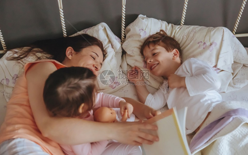 母亲给躺在床上的女儿和子看故事书的特写镜头周末家庭图片