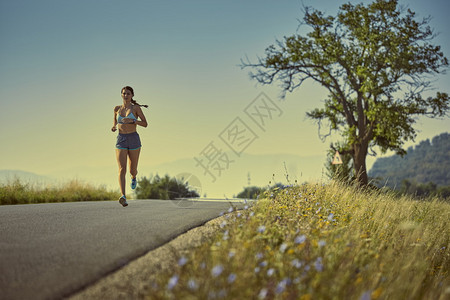 运动妇女清晨在一条公路上奔跑在自图片