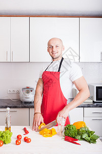 年轻的微笑男子在厨房做饭图片