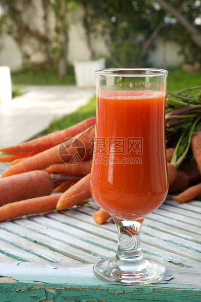 木质表面一杯新鲜的胡萝卜汁背景中图片