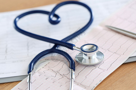 医疗听诊器扭曲的心形躺在心电图表特写医疗帮助预防疾病预防或保险概念心脏病学护理健康背景图片