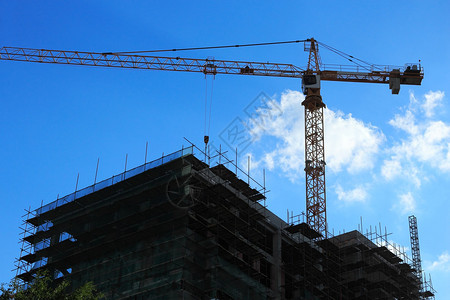 Crane和建筑工地的轮廓与明亮的蓝色天空图片