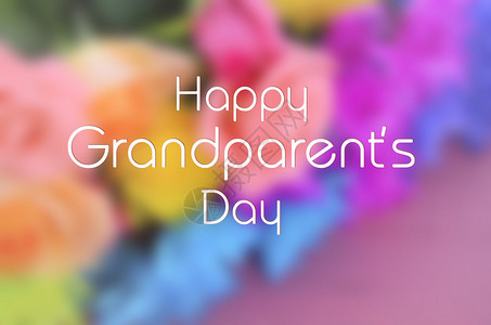 粉红木桌上鲜艳多彩鲜花的模糊背景与祖父母图片