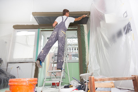 三十岁的体力工人在房子里用抹墙工具泥水匠用浮子和石膏翻新室内图片