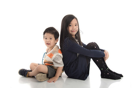 两个快乐的亚洲儿童坐着彼此依靠白种图片