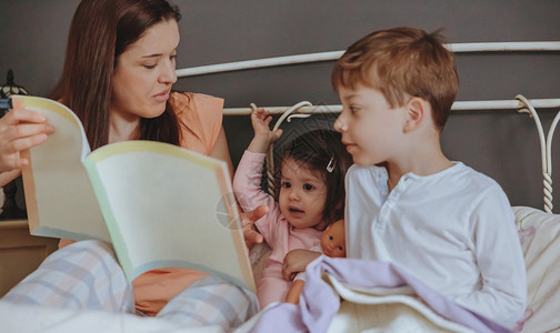 母亲给坐在床上的女儿和子看故事书的画像周末家庭图片