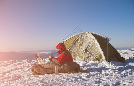 一个男人坐在帐篷附近的睡袋里图片