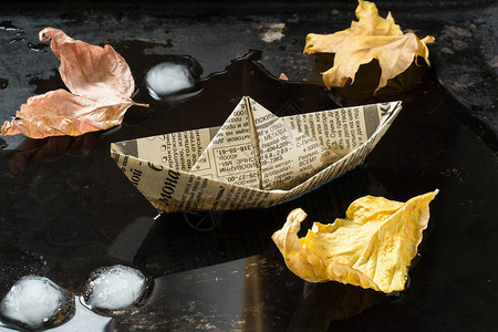秋天的情绪旧报纸上的折纸船在水图片