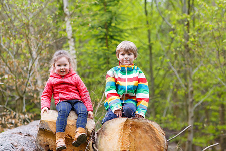 两个穿着鲜艳夹克的可爱微笑孩子在雨天一起在森林里散步兄弟姐妹之间的友谊幸图片