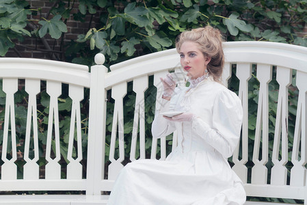 闺蜜喝茶坐在花园座位上喝茶的维多利亚时代的女人背景