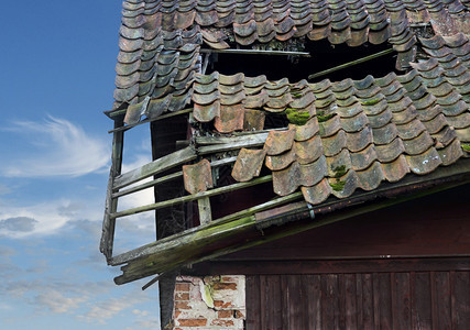 在明亮的天空倒塌的建筑物上的旧木屋顶图片