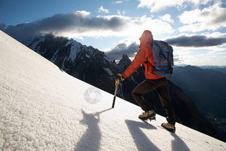 孤独的男登山者攀登雪脊图片