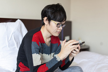 亚洲男人在床上玩手机图片