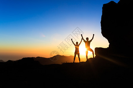 团队合作的情侣徒步旅行者在日落山上取得成功图片