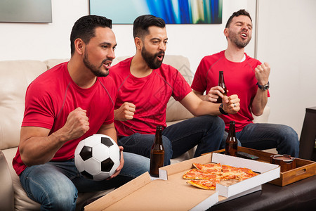 三个西班牙裔男朋友在电视上为足球队扎根图片