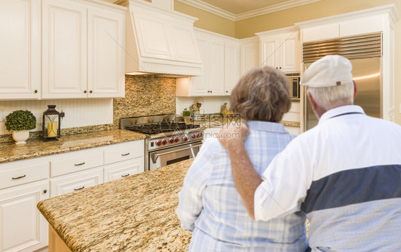快乐的老夫妇翻阅美丽的定制厨房设计图片