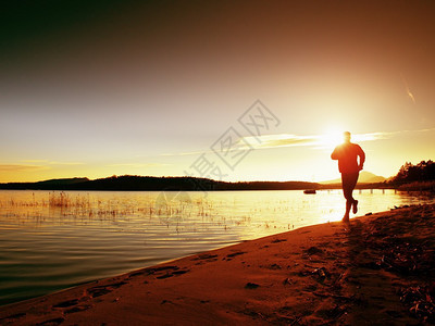 运动人早上在明亮的日出休眠室海滨慢跑图片