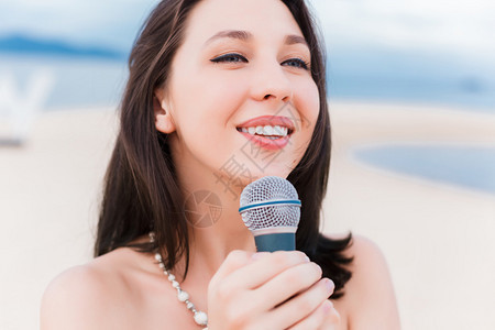 美丽的女孩歌唱在海滩图片