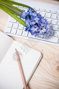 配有纸笔计算机键盘和鲜花的工作表图片