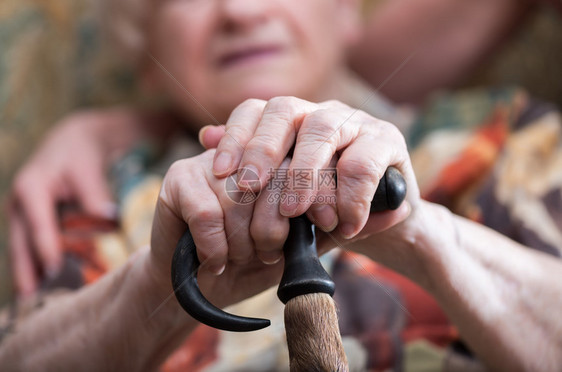 老妇人双手拄着拐杖坐着图片