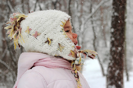 穿着温暖大衣和编织帽的幼儿女孩在冬季森林玩得开心图片
