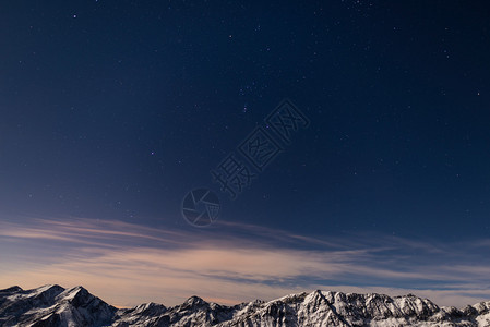 冬天在阿尔卑斯山拍摄的星空昴宿星猎户星座参宿四和天狼星清晰可见白雪皑的山脊在月光下发光图片