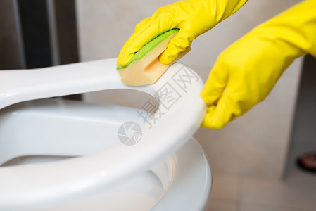 女手用黄色海绵在wc中清洁马桶座圈图片