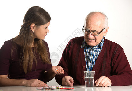 年轻妇女帮助老年男子在塑料杯图片