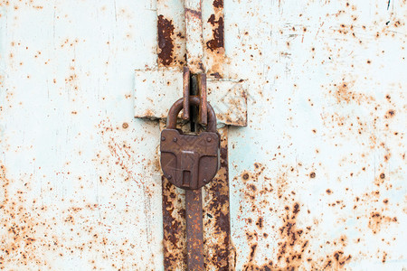 钢铁锁在生锈的灰色金属门上图片