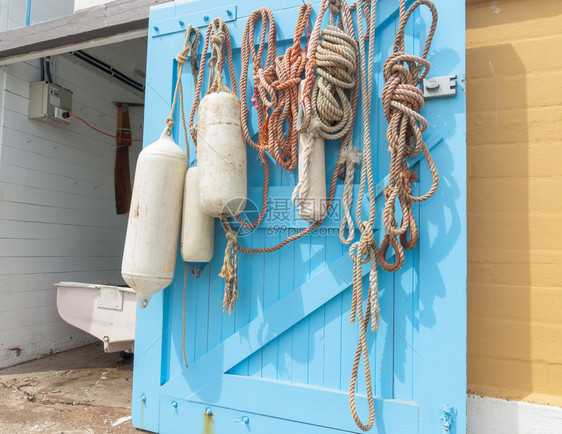 绳子和浮标挂在开阔的蓝色船舱门上图片