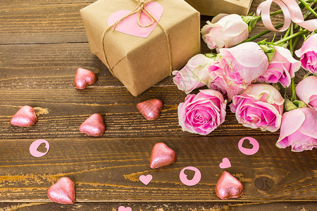 粉红玫瑰和礼物包装在生锈木板图片