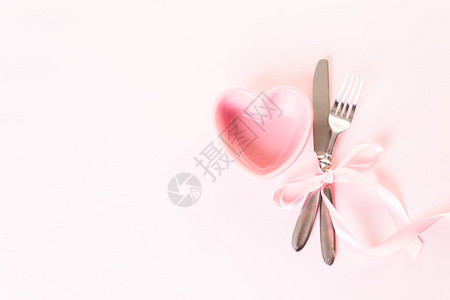 粉红色背景上带有粉红色丝带的餐具图片
