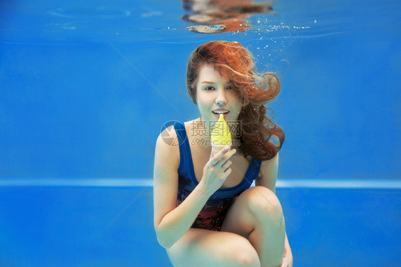 美丽的笑着的红发女孩夏天在水下游泳图片