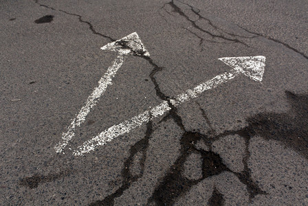 肮脏的沥青表面上的两个白色箭头交通标识图片