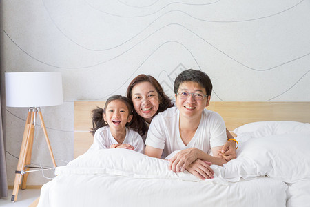 快乐的亚洲家庭母亲父亲和女儿在白床图片