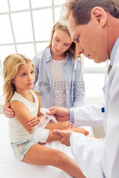 年轻中年儿科医生给小姑娘的手臂贴了绷带图片